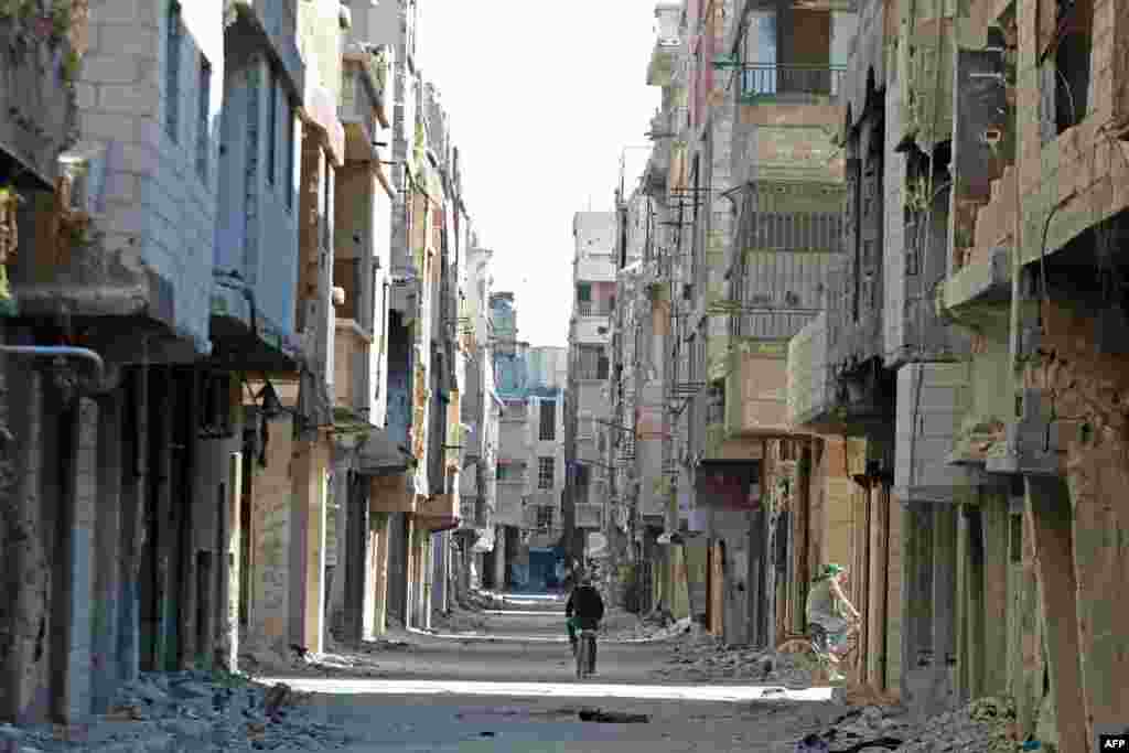 A man rides a bicycle past damaged buildings at the Yarmuk refugee camp in the southern suburbs of the Syrian capital Damascus. The regime of Syria's President Bashar al-Assad has recaptured vast territory from rebels and jihadists in the conflict that began in 2011.