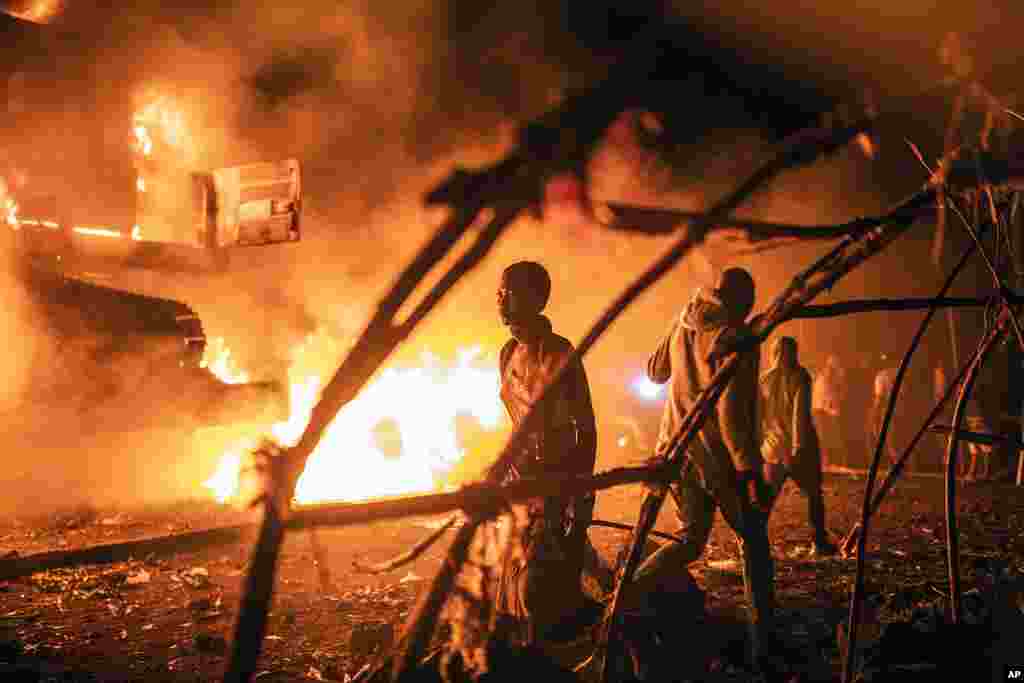 People walk by U.N. vehicles which were set on fire by angry crowds as frustrations mount over the advance of M23 rebels, in Goma, Democratic Republic of Congo, Nov. 1, 2022.