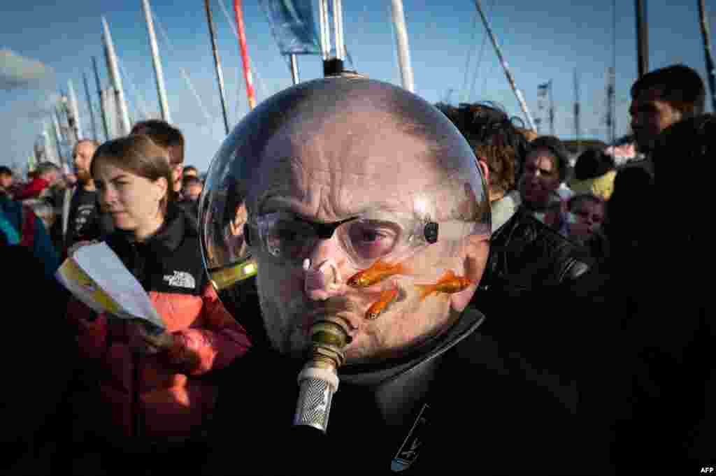 A man wearing an aquarium with goldfishes on his head walks among the pedestrians at the Village de Saint-Malo, the start point of the Route du Rhum solo sailing race, in Saint-Malo.