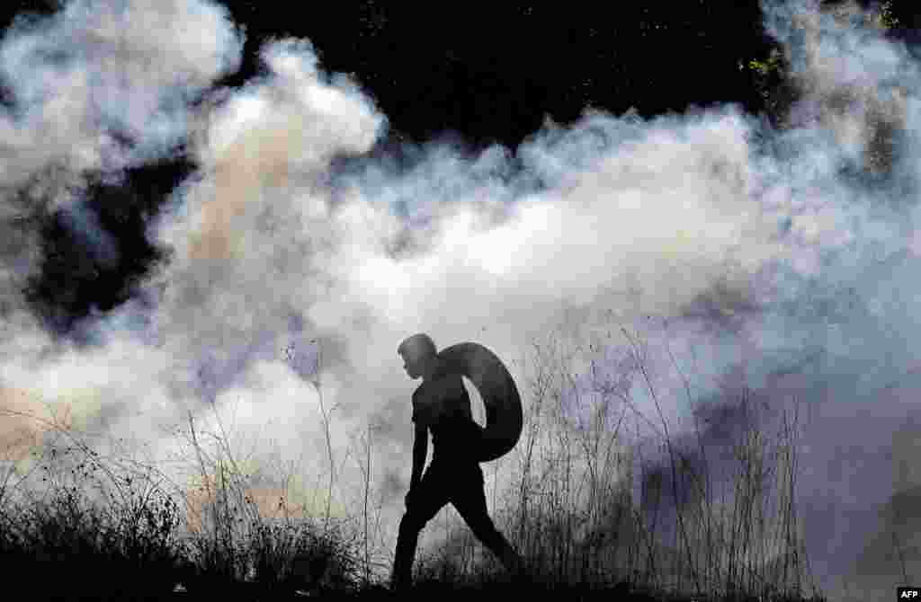 Palestinian demonstrators burn tires during a rally to protest the resumption of construction at the settlement outpost of Eviatar near the Palestinian village of Beita, south of Nablus in the occupied West Bank.