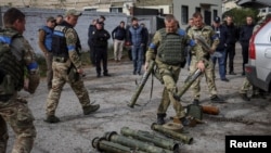 A police sapper sorts unexploded mine shells and weapons after return from the village of Udy, recently liberated by Ukrainian Armed Forces, in the town of Zolochiv, Kharkiv region, Ukraine September 12, 2022. (REUTERS/Gleb Garanich)