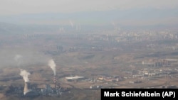 Asap dan uap tampak mengepul dari menara yang berada di area pembangkit listrik tenaga batu bara di Xinjiang, pada 21 April 2021. (Foto: AP/Mark Schiefelbein)