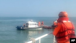 FILE — In this handout photograph provided by Taiwan Coast Guard Administration, Taiwanese coast guards inspect a vessel that capsized during a chase off the coast of Kinmen archipelago in Taiwan, Feb. 14, 2024. 