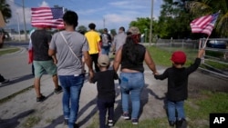 FILE - Carrying American flags, immigrants march during a peaceful protest against a Florida legislation restricting undocumented immigrants, Thursday, June 1, 2023, in Immokalee, Florida. (AP Photo/Rebecca Blackwell)