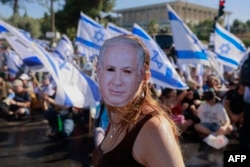 Seorang demonstran yang mengenakan topeng bergambar Perdana Menteri Israel Benjamin Netanyahu ikut serta dalam aksi duduk untuk memblokir pintu masuk Knesset, parlemen Israel, di Yerusalem, 24 Juli 2023. (Foto: AFP)