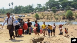 People cross the Moei river as they flee Myawaddy township in Myanmar to Thailand's Mae Sot town in Thailand's Tak province, April 20, 2024. 