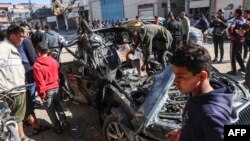 ARCHIVO - La gente revisa un automóvil en el que dos periodistas, Mustafa Thuria, un locutor de videos de la agencia de noticias AFP, y Hamza Wael Dahdouh, un periodista de la cadena de televisión Al Jazeera, fueron asesinados en la Franja de Gaza el 7 de enero de 2024.