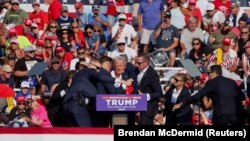 美國共和黨總統候選人、美國前總統特朗普(Donald Trump)在賓州巴特勒的競選集會上被槍手擊中右耳，隨後美國特勤局人員將他攙扶起來。 （2024年7月13日）
