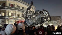People inspect a vehicle after what security sources said was a deadly drone strike, in Baghdad, Iraq, Feb. 7, 2024.