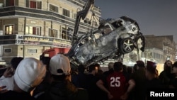 People inspect a vehicle after what security sources said was a deadly drone strike, in Baghdad, Iraq, Feb. 7, 2024.