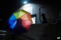 FILE - Central Bucks School District high school student Leo Burchell waits for a school board meeting to start, opening his rainbow colored umbrella as it begins to rain in Doylestown, Pa., on Tuesday, Nov. 15, 2022.(AP Photo/Ryan Collerd)