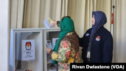 Seorang anggota KPPS) di TPSLN Las Angeles membantu pemilih memasukkan surat suara ke kotak suarai, Sabtu, 10 Februari 2024. Para pemilih di luar negeri hanya bisa memilih calon presiden/calon wakil dan calon anggota legislatif (caleg) DPR RI. (Foto: Rivan Dwiastono/VOA)