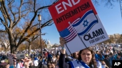 A woman holds a sign calling for an end to antisemitism while attending a March for Israel rally Nov. 14, 2023, on the National Mall in Washington. 