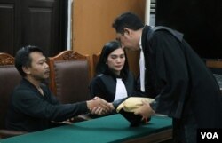 Kuasa hukum tersangka memberikan uang bantuan sebesar 200 juta rupiah kepada ayah Siti Khotimah, Suparna (kiri) dalam sidang putusan tindak kekerasan majikan terhadap PRT, yang berlangsung di Pengadilan Negeri Jakarta Selatan, Senin (24/7) sore.(VOA/Indra Yoga)