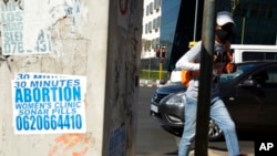 FILE - A pedestrian walks past a sign pasted on a sidewalk in Johannesburg, Aug. 18, 2020. 