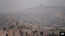 FILE - Syrians walk along in a refugee camp for displaced people run by the Turkish Red Crescent in Sarmada district, north of Idlib city, Syria, on Nov. 26, 2021.