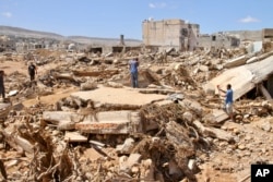 Warga mencari korban selamat di Derna, Libya, Rabu, 13 September 2023. Tim pencari menyisir jalan, menghancurkan bangunan, bahkan laut untuk mencari jenazah di Derna, tempat runtuhnya dua bendungan yang memicu banjir bandang besar yang menewaskan ribuan orang. (Foto: AP)