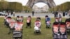 Sejumlah kereta bayi berisi foto dari para anak-anak yang disandera oleh militan Hamas ditampilkan dalam aksi demo di depan Menara Eiffel di Paris, pada 26 Oktober 2023. (Foto: AFP/Dimitar Dilkoff)