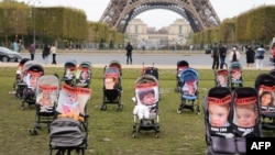 Sejumlah kereta bayi berisi foto dari para anak-anak yang disandera oleh militan Hamas ditampilkan dalam aksi demo di depan Menara Eiffel di Paris, pada 26 Oktober 2023. (Foto: AFP/Dimitar Dilkoff)