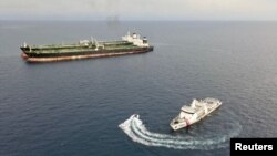 Kapal patroli KN. Pulau Marore-322 milik Bakamla menginspeksi kapal MT Arman 114 berbendera Iran, dan MT S Tinos berbendera Kamerun, saat terlihat melakukan pelayaran kapal- transfer minyak ke kapal tanpa izin, dekat Laut Natuna Utara, 7 Juli 2023 (Bakamla/ Handout via REUTERS)