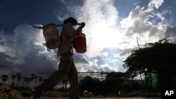 បុរសម្នាក់​ដើរ​នៅ​ក្រោម​ពន្លឹព្រះអាទិត្យ​ដ៏ក្តៅ​នៅជាយ​ទីក្រុង​ភ្នំពេញ​ប្រទេស​កម្ពុជា​កាលពី​ថ្ងៃទី​១៧ កក្កដា ឆ្នាំ២០២០។(AP Photo/Heng Sinith)