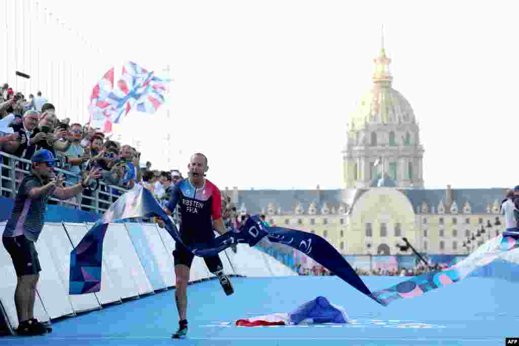 France's Jules Ribstein celebrates as he crosses the finish line to win the men's PTS2 para triathlon event at the Paris 2024 Paralympic Games at the Pont Alexandre III.
