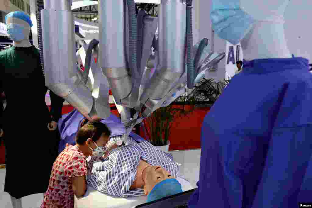 A child watches as a Shurui surgical robot, operated by a staff member (not pictured) from a console, performs "surgery" on a dummy at the World Robot Conference in Beijing, China.