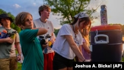 Pemandu kemping Izzy Kellar dari Dayton, Ohio, mengisi botol air peserta kemping, Kamis, 20 Juni 2024, di YMCA Camp Kern di Oregonia, Ohio. (Foto: AP/Joshua A. Bickel)