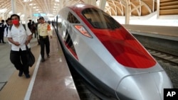 FILE - People walk near a high-speed train during its testing phase at Halim station in Jakarta, Indonesia, Sept. 18, 2023.