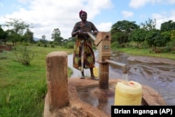 Rhoda Peter fills containers with water from a sand dam in Makueni County, Kenya on Friday, March 1, 2024. She was fetching water to clean utensils and wash clothes. (AP Photo/Brian Inganga)