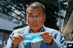 FILE - Hong Kong media tycoon Jimmy Lai, who founded the local newspaper Apple Daily, prepares to wear a face mask before entering a court in Hong Kong on May 5, 2020. (AP Photo/Kin Cheung, File)