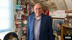 Jonathan Salant stands in front of the hundreds of press passes he has collected over his decades of reporting on Washington. (Liam Scott/VOA)
