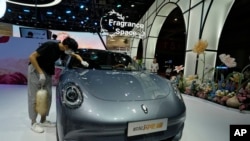 FILE - A worker wipes an Ora, a Chinese electric car, at a car show in Shanghai, April 18, 2023. As China's leaders prepare to discuss economic and political policy measures, concerns are growing about the effect of China's economy, including EV manufacturing, on worldwide trade.