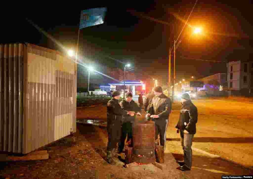 Los tártaros de Crimea se calientan alrededor de una hoguera mientras vigilan su barrio el 9 de marzo. El primer ministro interino de Ucrania, Arseniy Yatsenyuk, dijo que Ucrania no cedería "ni una pulgada" de su territorio mientras la toma rusa de Crimea se solidificaba y la vida se volvía cada vez más peligrosa para los locales que se oponían a la anexión ilegal.