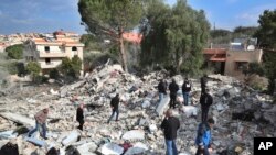 FILE - Lebanese citizens gather on the rubles of a house that was destroyed by an Israeli airstrike Tuesday night, in Bint Jbeil, south Lebanon, Dec. 27, 2023.