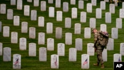 FILE - A member of The Old Guard, places flags in front of each headstone for "Flags-In" at Arlington National Cemetery in Arlington, May 25, 2023, to honor the Nation's fallen military heroes ahead of Memorial Day. (AP Photo/Andrew Harnik, file)
