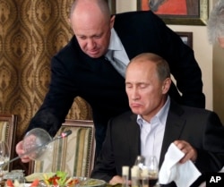 Yevgeny Prigozhin, atas, menyajikan makanan kepada Vladimir Putin di restoran Prigozhin di luar Moskow, Rusia pada 11 November 2011. (Foto: AP)