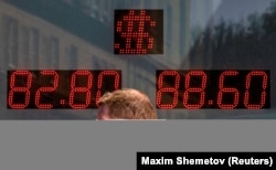 Seorang pria berjalan melewati papan yang menunjukkan nilai tukar dolar AS dan Euro terhadap rubel Rusia di Moskow, Rusia, 19 Juni 2024. (Foto: REUTERS/Maxim Shemetov)