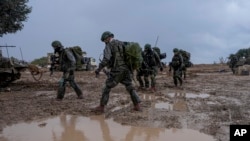 Israeli soldiers prepare to enter the Gaza Strip, at a staging area near the Israeli-Gaza border, in southern Israel, Dec. 13, 2023.