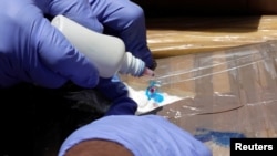 ARCHIVO - Un miembro de la policía federal prueba un paquete de cocaína incautado durante la actual administración, antes de incinerarlo, en un campamento del batallón de infantería 37A del Ejército Mexicano en San Juan Teotihuacán, México, 4 de mayo de 2018.