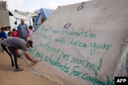 Muškarac piše poruku zahvale studentima u SAD koji protestuju u znak solidarnosti sa narodom Gaze, u šatoru u kampu za raseljene Palestince u Rafi, u južnom pojasu Gaze, 27. aprila 2024.