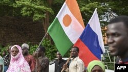 Des drapeaux nigérien et russe tenus par des citoyens au stade Général Seyni Kountche à Niamey, le 26 août 2023. AFP
