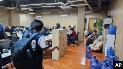 FILE - In this photo provided by the Philippine National Police Anti-Cybercrime Group, police raid an office in Las Pinas, Philippines, on June 27, 2023. The UN says criminal gangs have forced hundreds of thousands of people in Asia into participating in online scam operations.