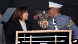 El cadete Melic Belong entrega a la vicepresidenta Kamala Harris un recuerdo durante la ceremonia de graduación de los cadetes de la academia militar de Estados Unidos en West Point, Nueva York, sábado 27 de mayo de 2023. (AP Foto/Bryan Woolston)