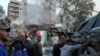 People gather near a damaged site, hauling a destroyed vehicle away, after what Syrian and Iranian media described as an Israeli airstrike on Iran's consulate in the Syrian capital Damascus, April 1, 2024.