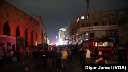 دیمەنی گردبوونەوەی هاوڵاتی و دوکانداران لەبەردەم بازاڕی قەیسەری هەولێر لە کاتێکدا تیمەکانی فریاکەوتن سەرقاڵی کۆنترۆڵکردنی ئاگرەکەن.