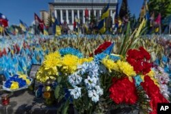 Various flowers are seen in front of a field of flags in memory of fallen fighters, in Kyiv, Ukraine, June 25, 2024. Despite hardships brought by war flowers fill Kyiv and other Ukrainian cities.