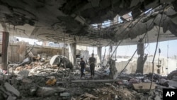 Des Palestiniens se tiennent dans les ruines d'une maison familiale, détruite par une frappe israélienne qui aa ussi tué au moins deux adultes et cinq garçons et filles de moins de 16 ans à Rafah, dans le sud de la bande de Gaza, le vendredi 3 mai 2024. (AP/Ismaël Abou Dayyah)