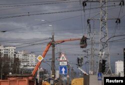 FILE - Energy supply workers restore a high-voltage line destroyed in Russian missile attack, amid Russia's attack on Ukraine, in Kyiv, Feb. 7, 2024.