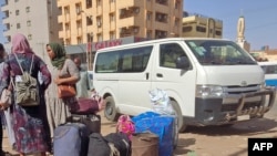 Watu wakiwa na mizigo yao wakisubiri kwenye kituo cha basi kilichopo kusini mwa Khartoum, tarehe 8 Mei 2023. Picha na AFP. 
